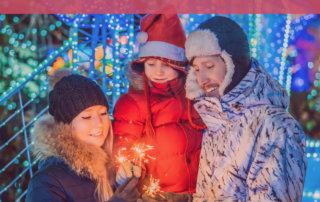 family in winter clothes lighting a sparkler outside