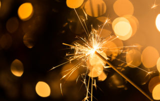 Extra long even sparkler lit with gold bokeh background