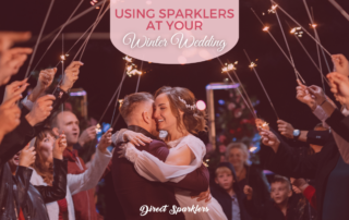Couple hugging surrounded by guests with lit sparklers