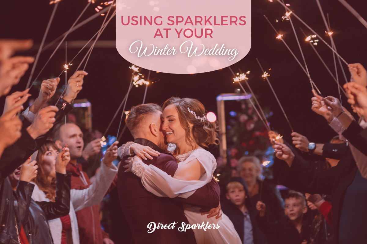 Couple hugging surrounded by guests with lit sparklers